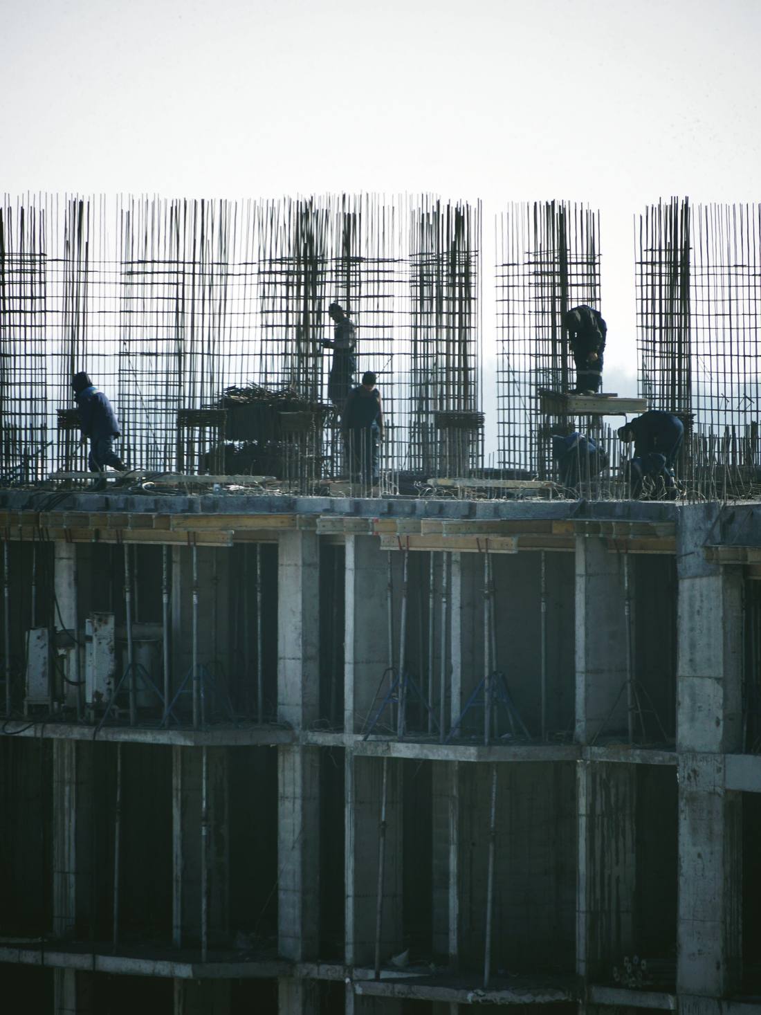 Workers fixing rebar on a high-rise construction site